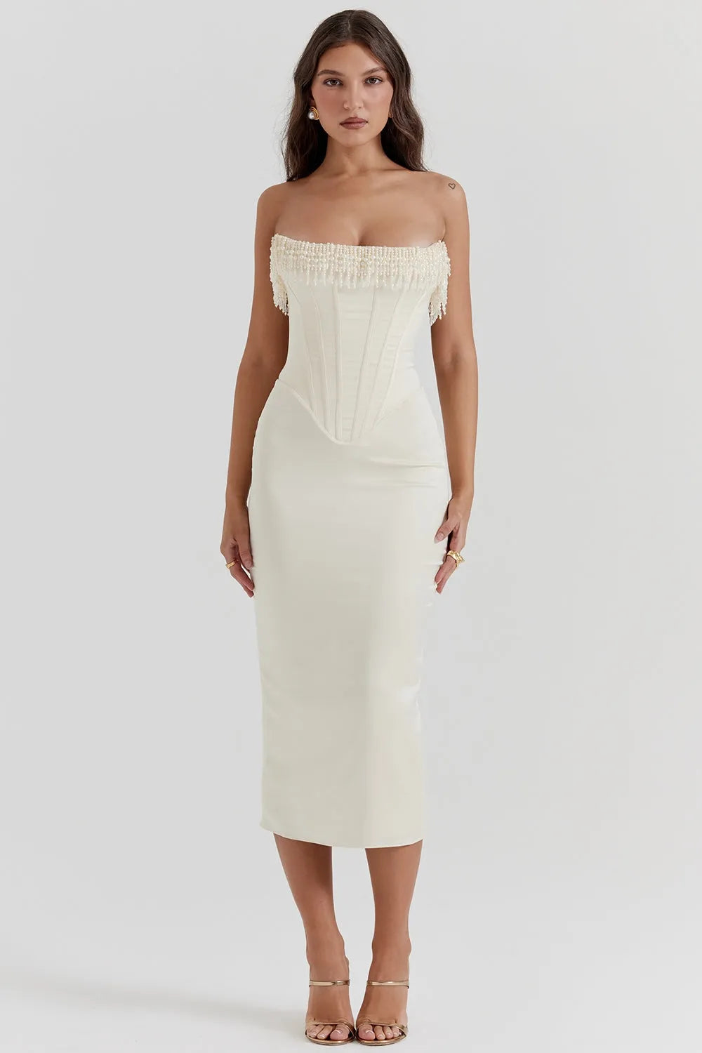 Modelo usando vestido midi blanco sin tirantes con detalle de perlas en el busto. Corte elegante ideal para boda civil o eventos formales.