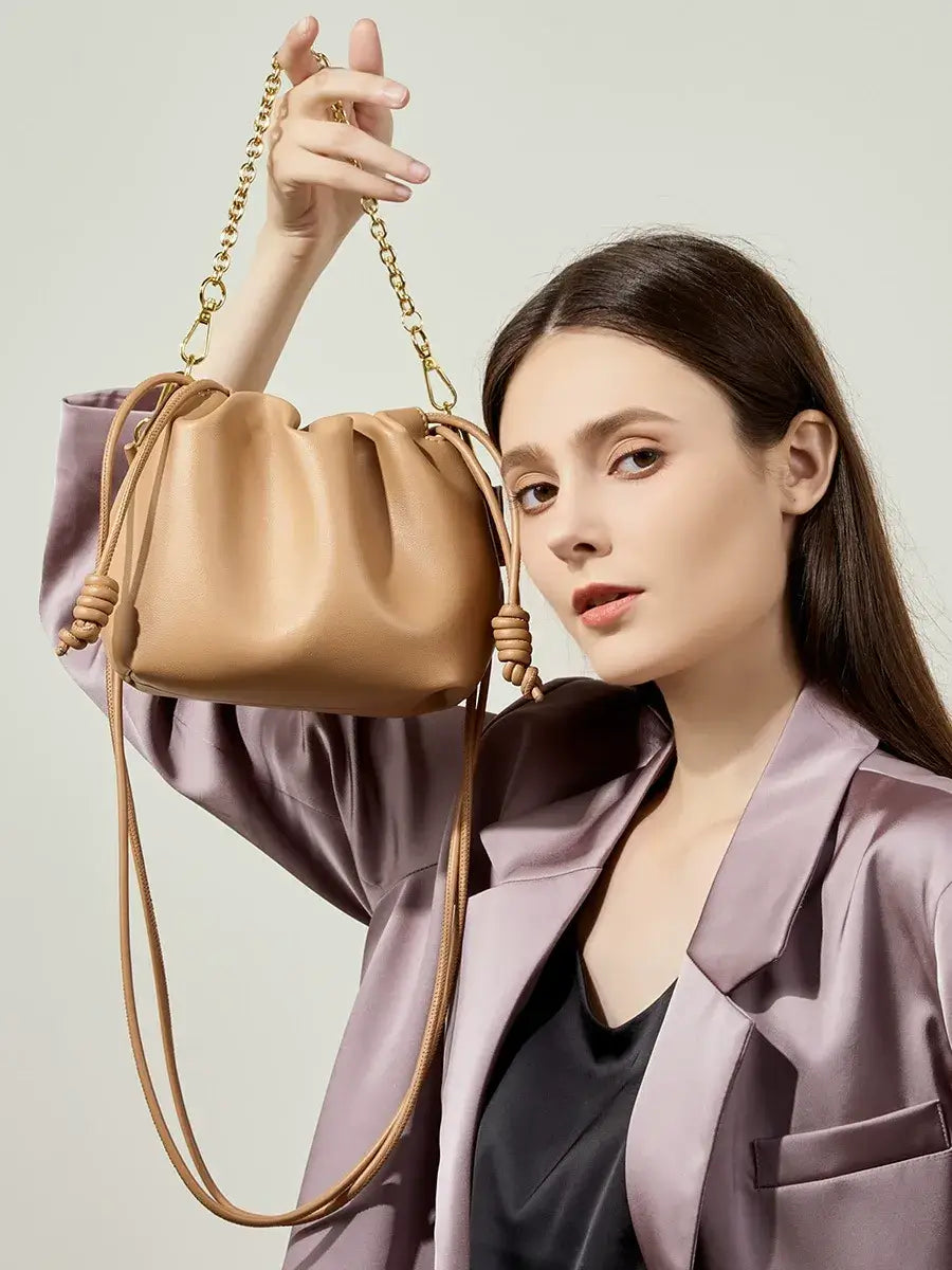 Mujer sosteniendo bolso pouch Aurelia café con cadena dorada – Veliara