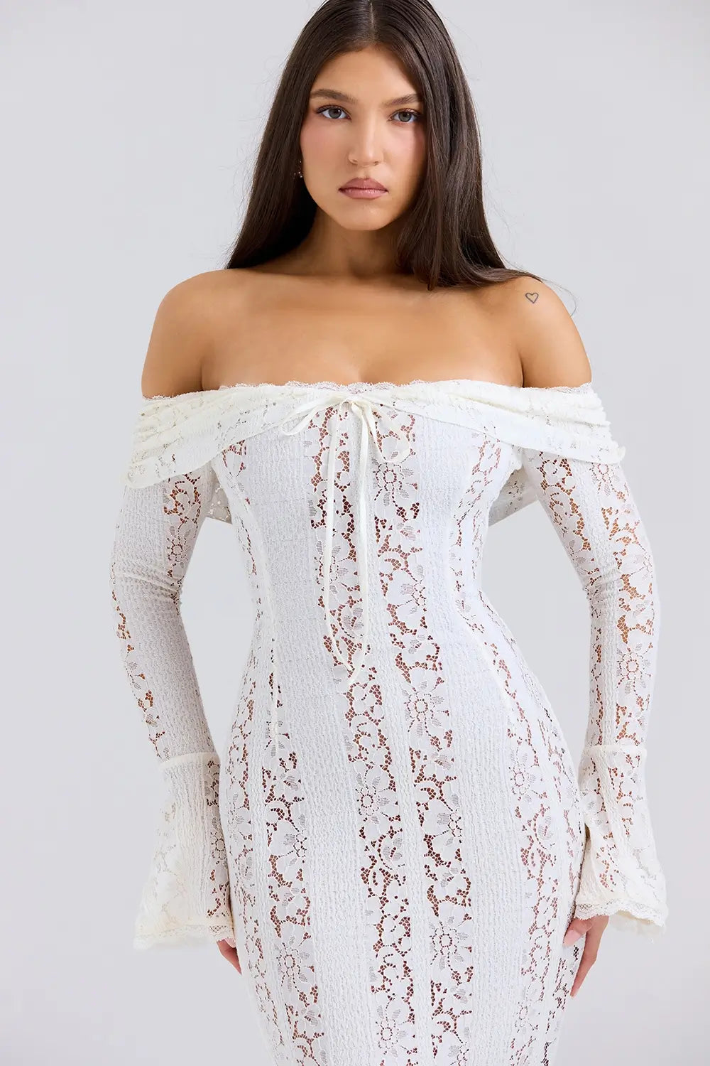 Vestido largo elegante para mujer con encaje floral vintage, diseño off-shoulder con escote corazón, mangas largas y abertura frontal. Ideal como vestido de gala, vestido para boda o vestido de noche sofisticado. El corte favorece la silueta femenina con un estilo romántico y moderno. Perfecto para invitadas de boda, cenas formales y eventos especiales. Vestido con forro completo y acabado premium, perteneciente a la colección edición limitada de Veliara.