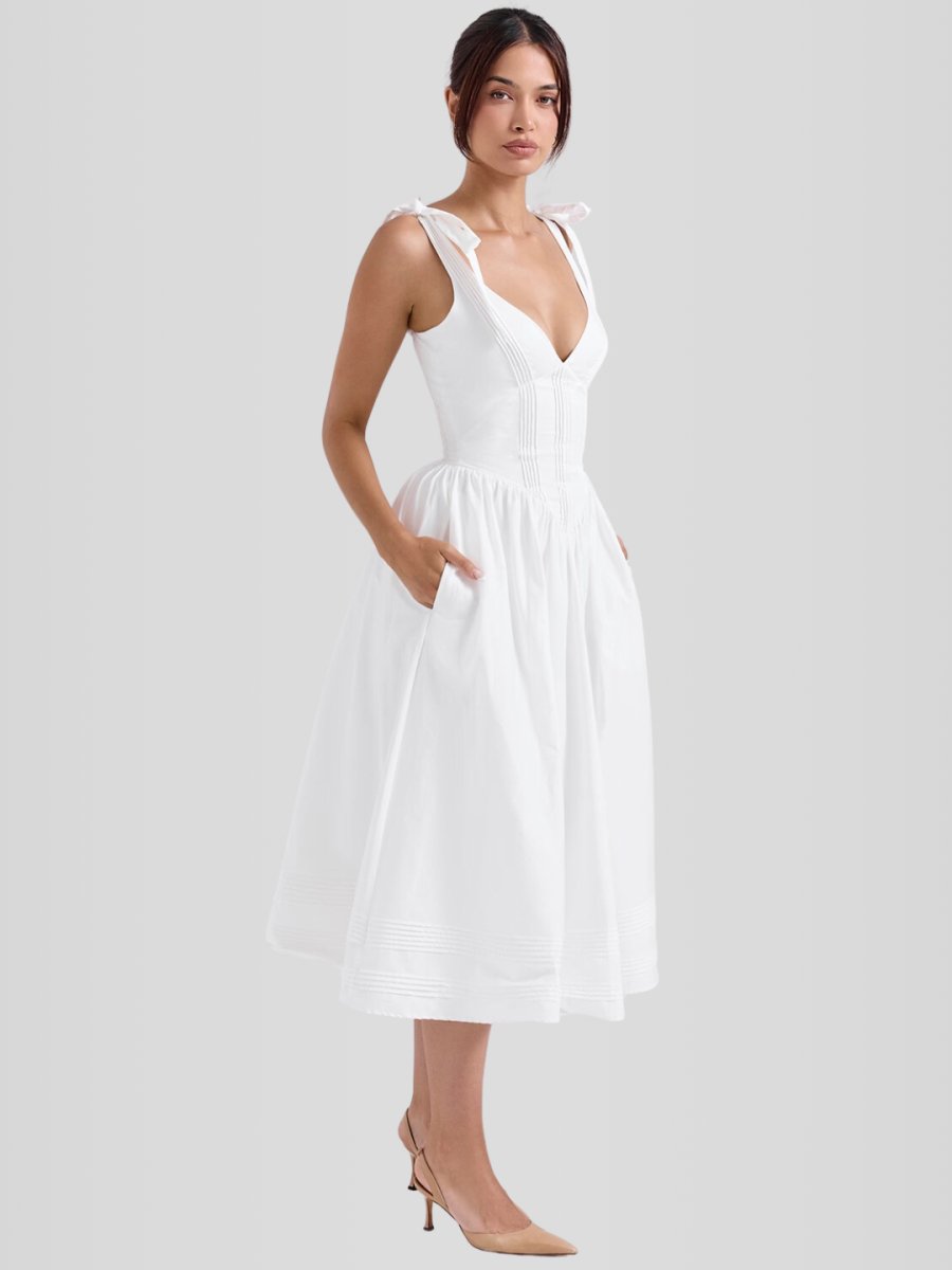 Modelo usando vestido midi blanco sin mangas con corset estructurado y ballenas internas. Diseño elegante con bolsillos discretos y ajuste entallado.
