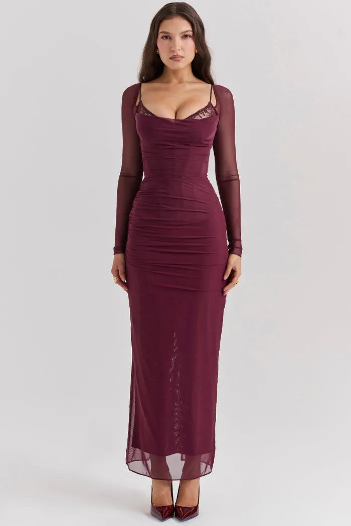 Modelo usando vestido largo color vino con corset y encaje, manga larga semitransparente y falda fluida para eventos de noche.