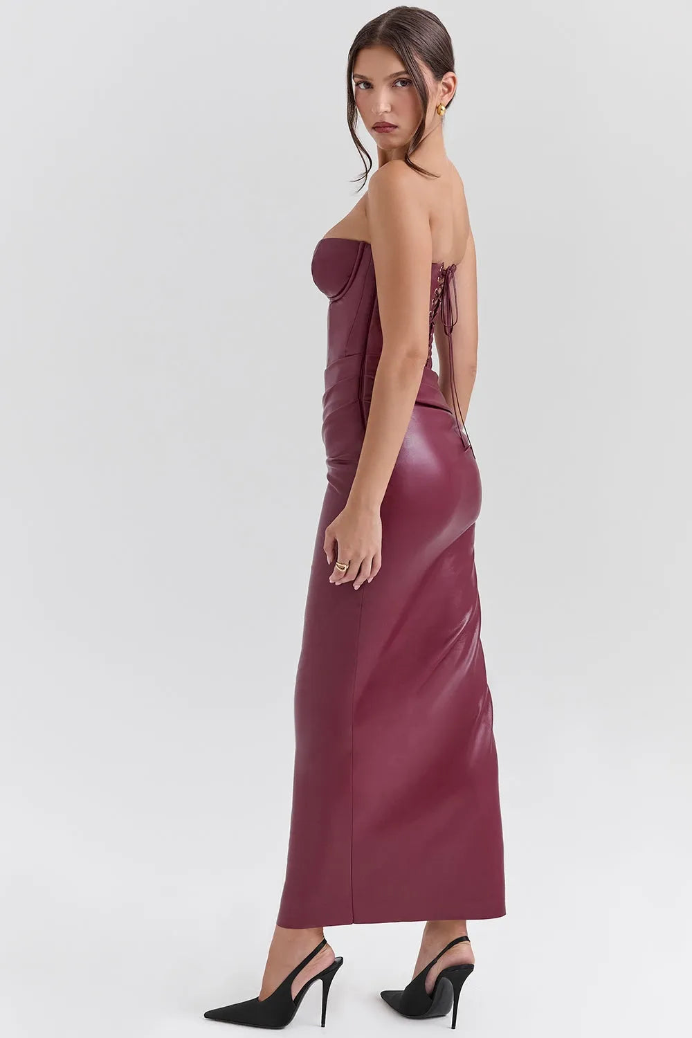 Mujer usando un vestido largo elegante en cuero vegano color vino, con corset estructurado sin tirantes y abertura lateral, ideal para gala o eventos de noche.